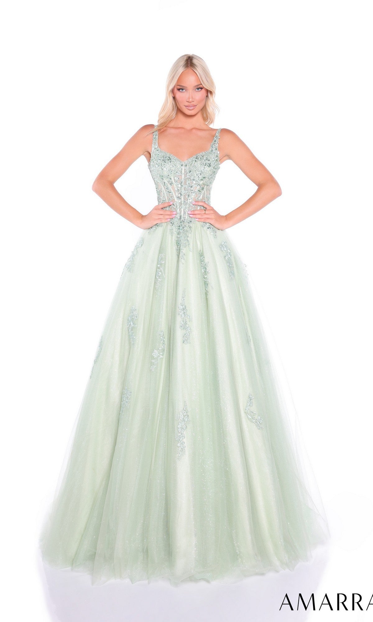A woman poses with hands on hips against a white background in the sage Sheer-Corset Long Prom Dress, Amarra 89429, featuring a light green embellished A-line silhouette and an embroidered bodice. The “AMARRA” logo appears in the corner.
